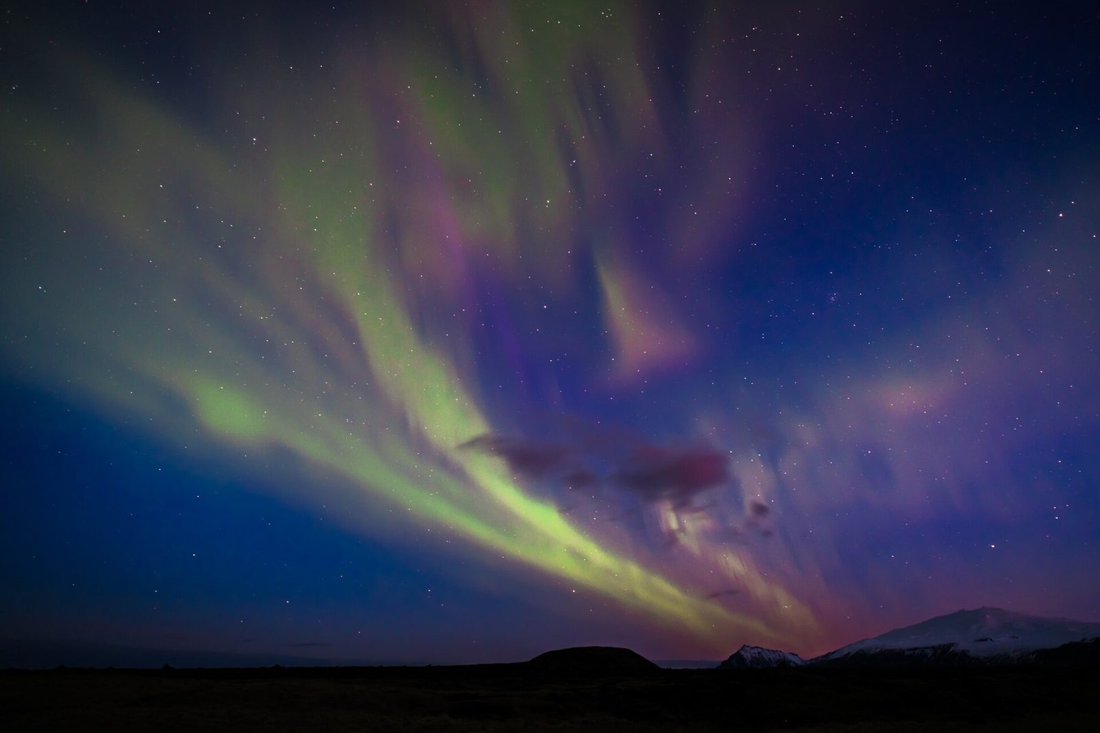 The northern lights glowing over a mountain landscape in Iceland