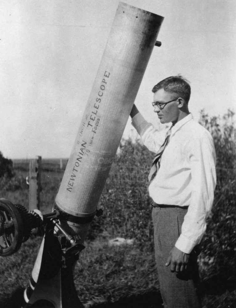 Clyde Tombaugh around 1930, standing beside the 9-inch Newtonian reflector he built himself on his family&rsquo;s Kansas farm, its tube hand-lettered with the aperture and focal length