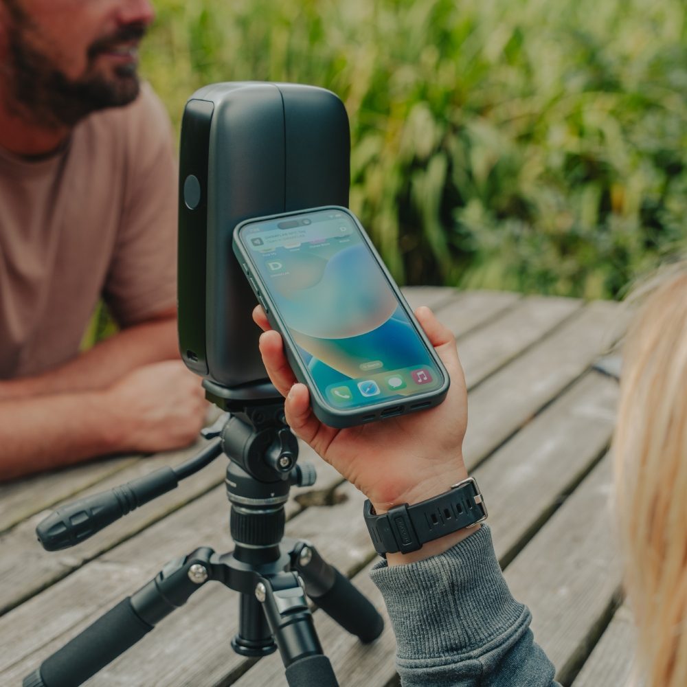 A phone pairing with a DwarfLab Dwarf Mini smart telescope on a picnic table