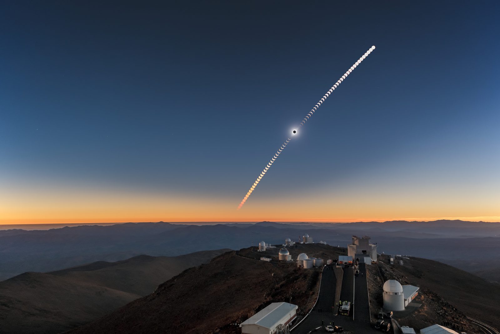 Every stage of a total solar eclipse — from first bite to totality and back — arcing over the telescope domes of La Silla Observatory