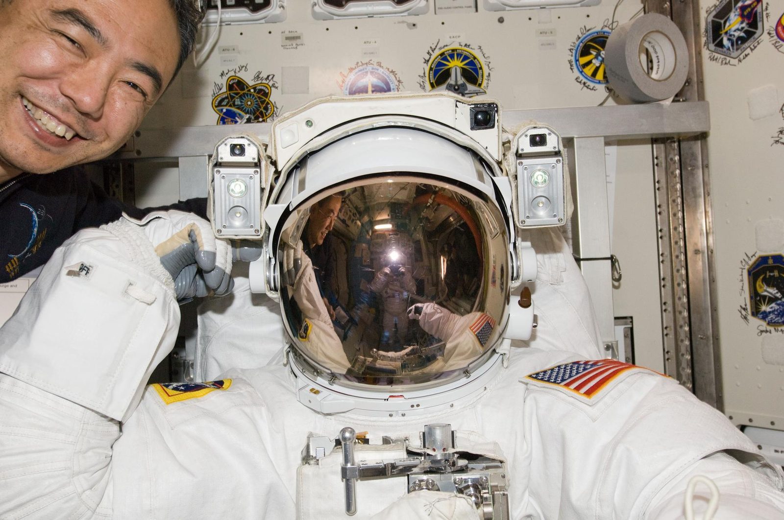 An astronaut in a white EMU spacesuit with the gold-visored helmet down, during a spacewalk rehearsal aboard the International Space Station