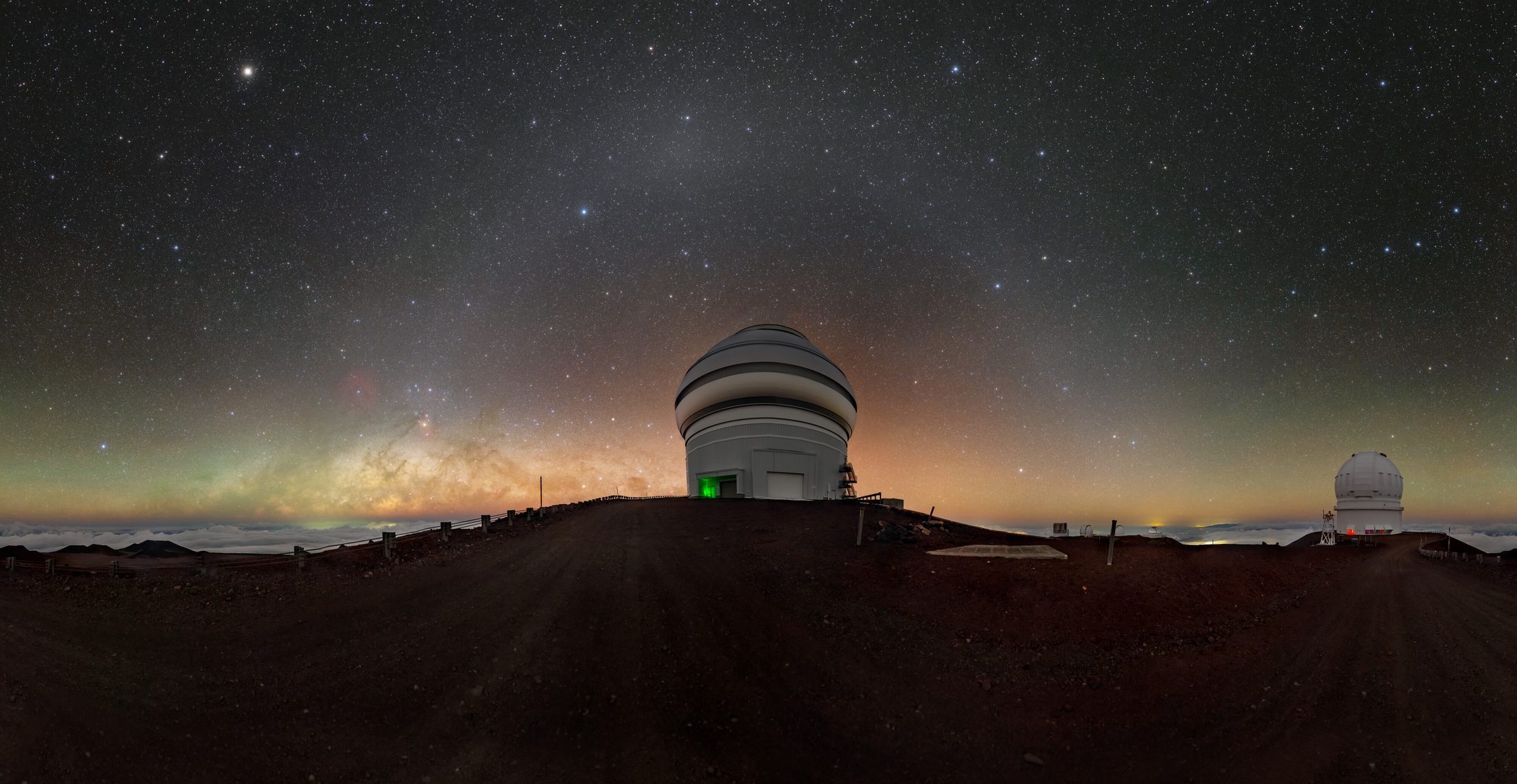 The Gemini North telescope dome on the Maunakea summit under a star-filled sky, with the Milky Way and green airglow low over the horizon