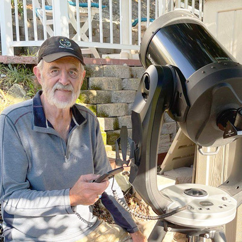 Dr. Leon Palmer in a Rigel Systems cap beside a Schmidt-Cassegrain telescope in his backyard