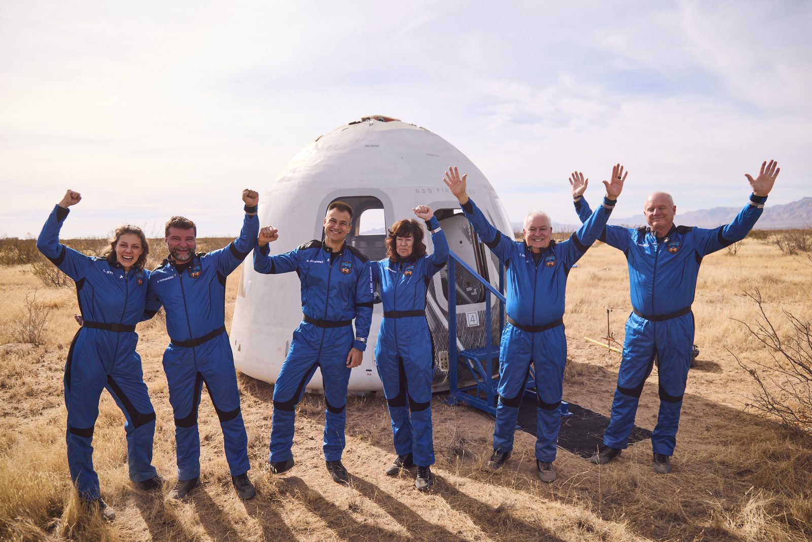 A New Shepard crew celebrating beside their capsule after landing in the West Texas desert