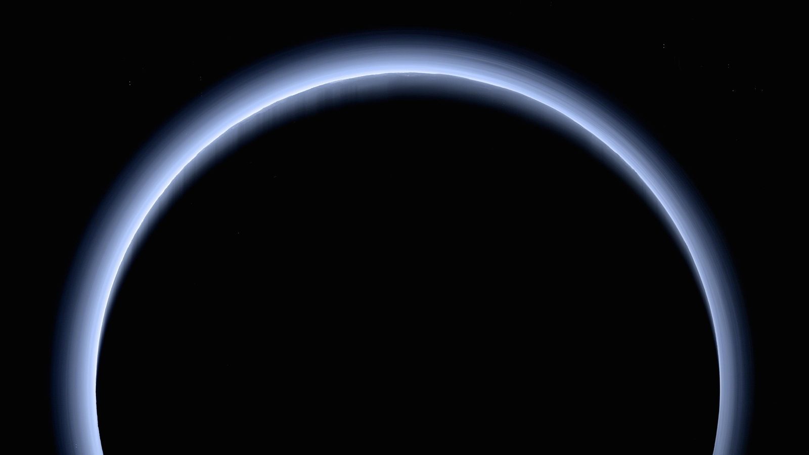 Pluto&rsquo;s atmosphere glowing blue in a ring around the dark planet, backlit by the distant Sun &mdash; New Horizons&rsquo; farewell look back after its July 2015 flyby
