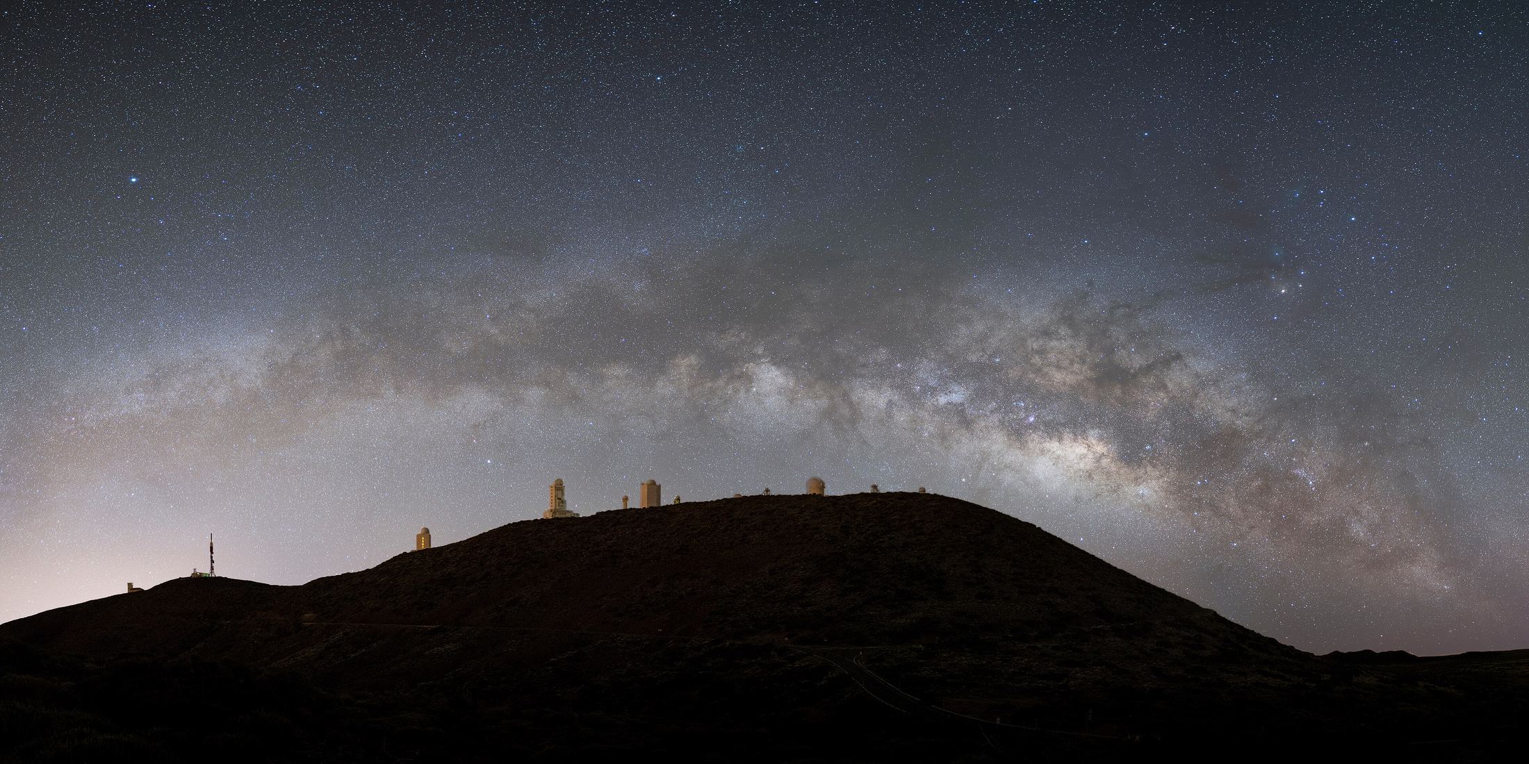 The Milky Way arching over the telescope domes of the Teide Observatory at Iza&ntilde;a, Tenerife, photographed from Teide National Park