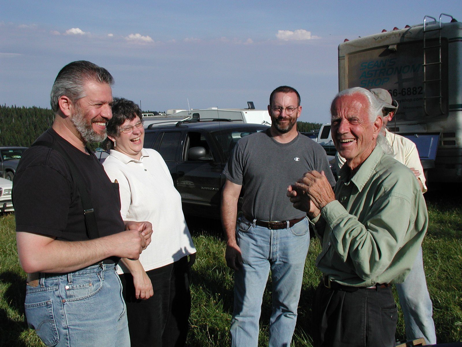 Carl Zambuto and John Dobson laughing together on the field at the Table Mountain Star Party, with Chuck Smith and his wife beside them